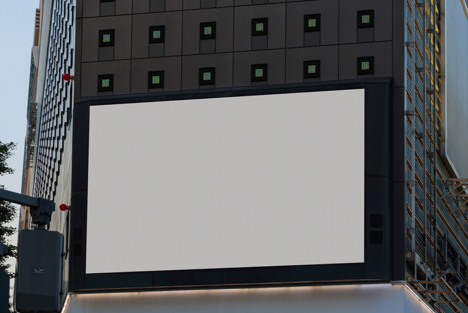 Large blank digital billboard mounted on dark high-rise facade midtown