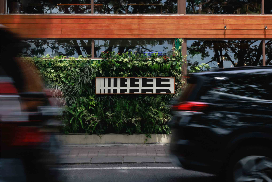 Geometric text display on overgrown planter signage with motion-blurred traffic