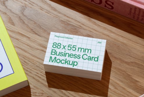 Business card mockup on wooden table featuring 88x55mm size in grid design for designers. Perfect for branding, layout previews, marketing presentations.
