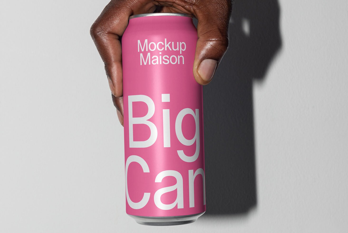 Hand holding a pink can featuring white text Big Can Mockup Maison. Ideal for designers seeking beverage packaging mockup for branding presentations.