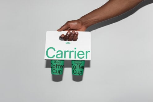 Hand holding a coffee cup carrier with green text branding. Ideal mockup for designers focusing on packaging, typography, and branding projects.