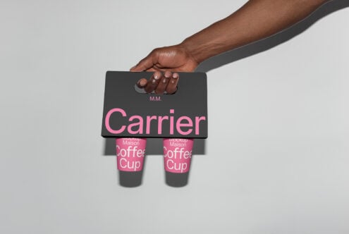 Mockup of a hand holding a modern black coffee cup carrier with pink design ideal for packaging design and branding. Keywords: mockup, graphic design