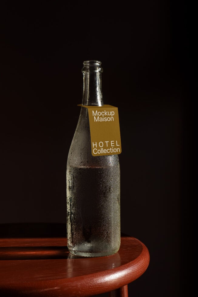 Frosted beer bottle with gold label on wooden round table against black