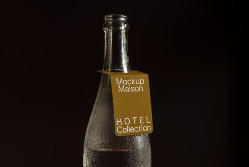 Glass bottle mockup with golden label in dark background showcasing customizable design perfect for hotel branding and product presentations.