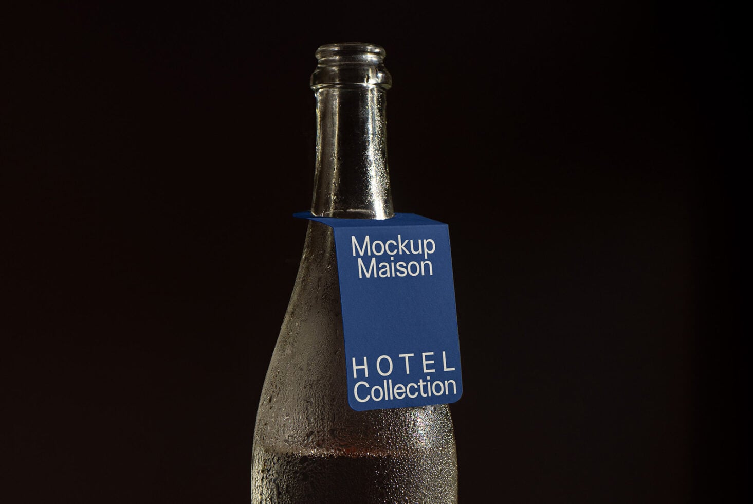 Cold bottle with blue label sitting on dark wood surface, studio shot