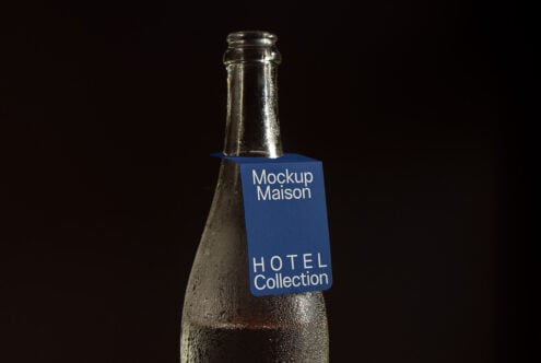 Glass bottle mockup with blue tag against dark background suitable for hotel branding design. Ideal for designers seeking exclusive mockups or templates.