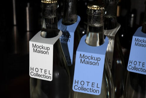 Glass bottles with rectangular tags labeled Mockup Maison Hotel Collection in blue and white perfect for showcasing branding templates and label designs