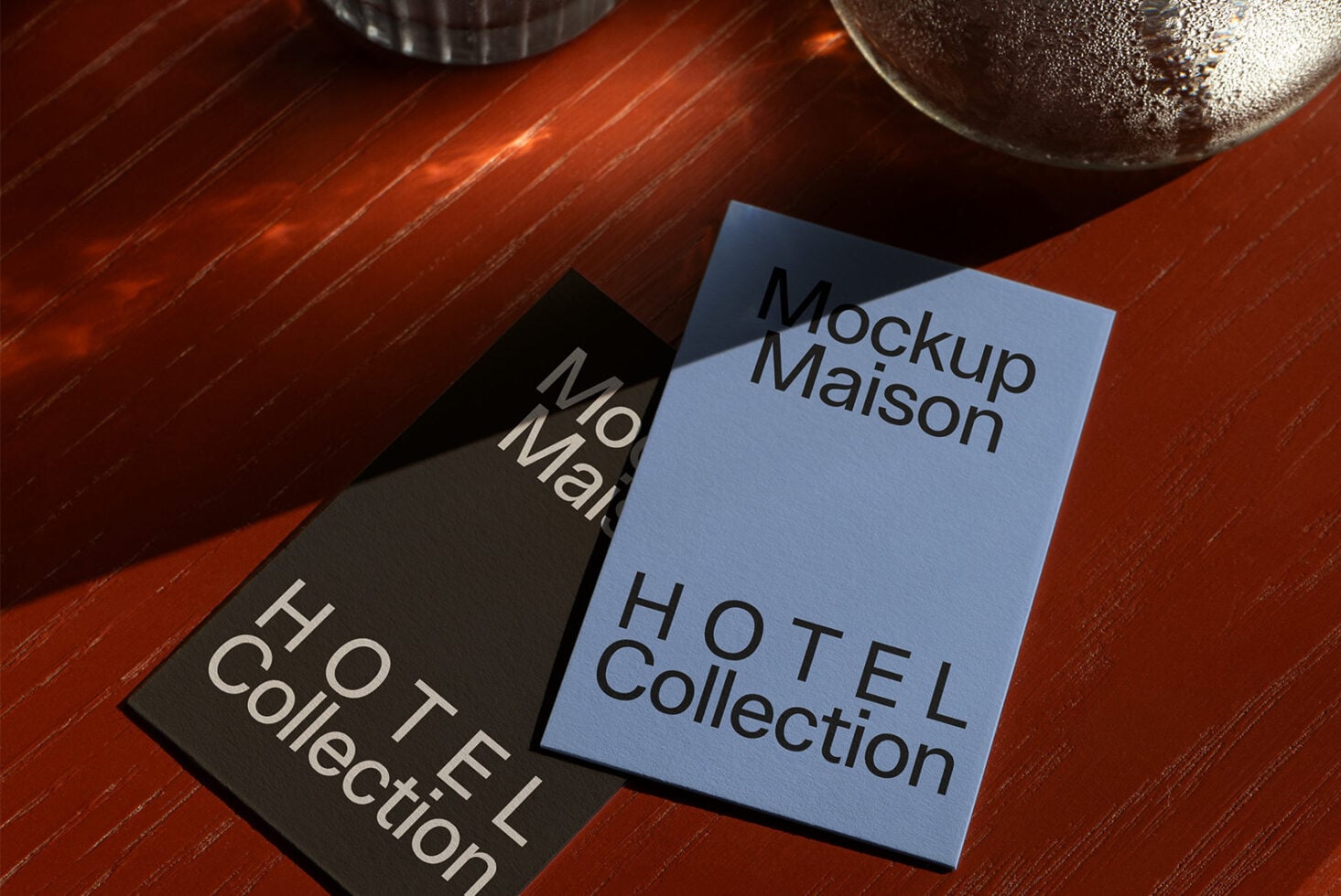 Black card next to periwinkle card on wooden table with beverage glass