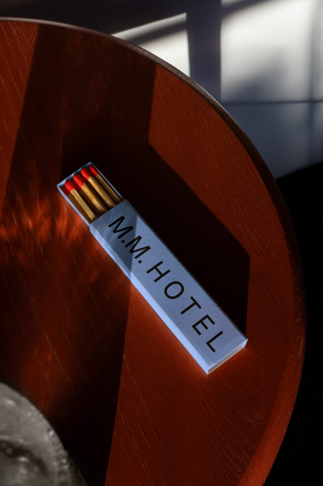 Matchbox with red tips on a deep red wooden curved surface in bright daylight