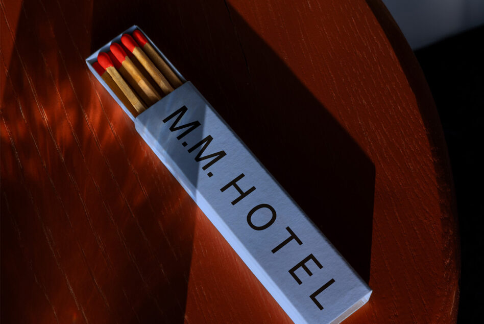 Light blue matchbox with red match tips positioned diagonally on wooden backdrop