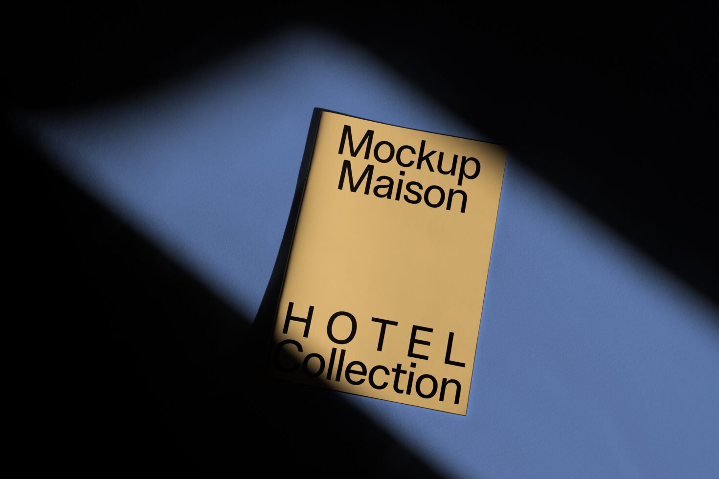 Yellow booklet on a blue surface with elegant shadows reads Mockup Maison Hotel Collection. Perfect for design templates and mockup demonstrations.