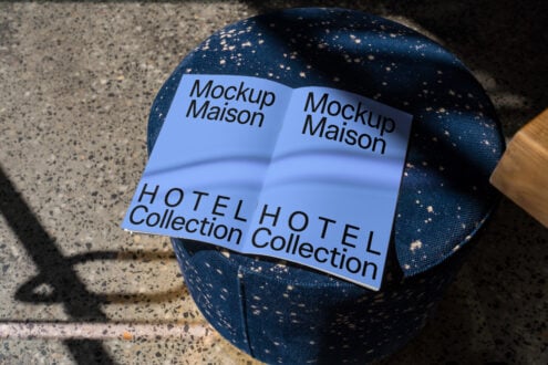 Open magazine mockup on a blue fabric stool featuring Hotel Collection text suitable for designers. Ideal for showcasing branding and print designs.