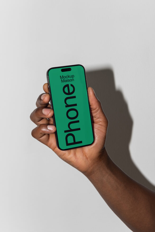 Hand holding a smartphone with green screen displaying text Phone Mockup Maison perfect for digital mockups designers high-quality graphic templates.