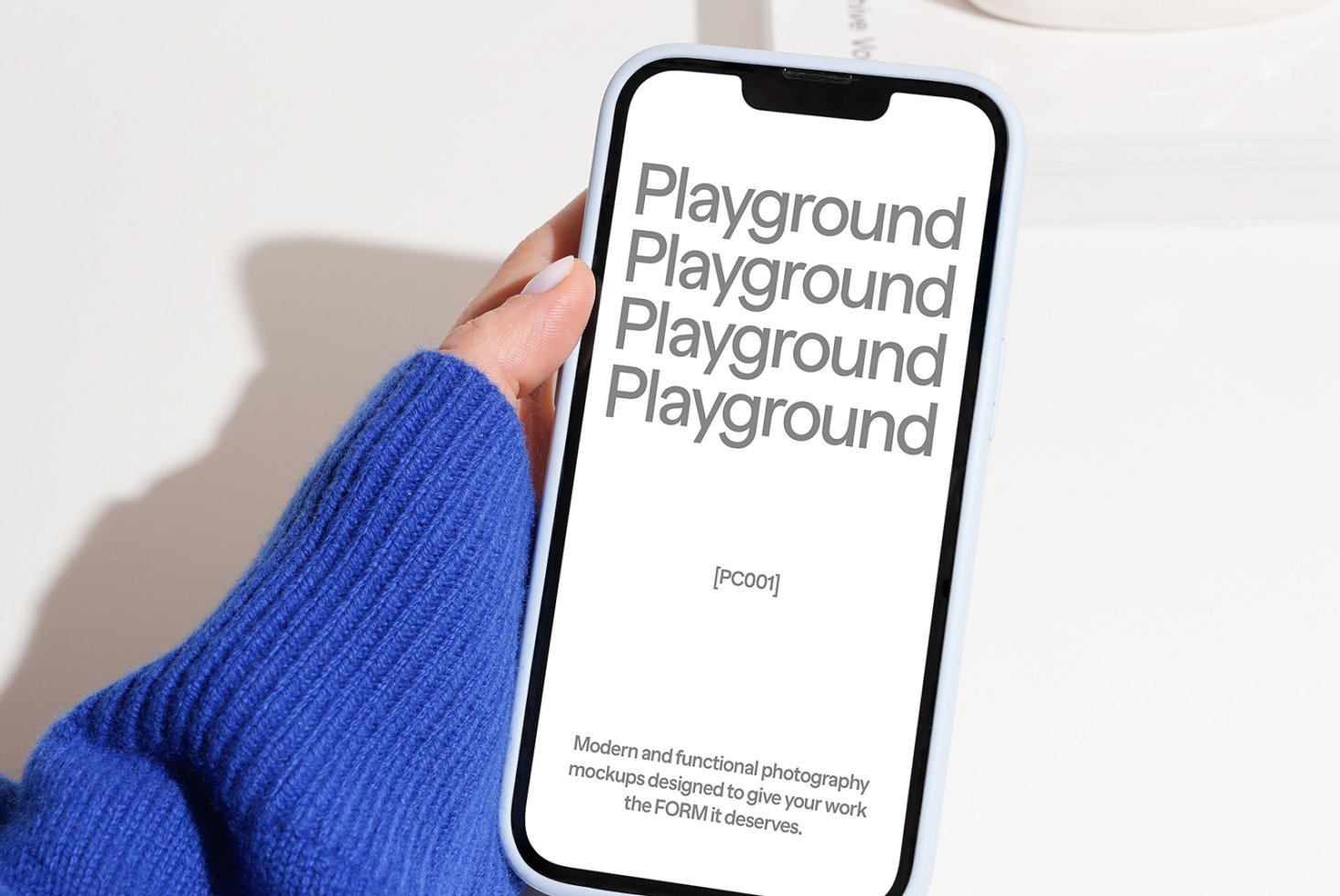 Phone mockup held in hand wearing blue sleeve displaying text Playground. Perfect for designers needing modern digital assets and photography mockups.