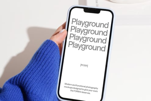 Phone mockup held in hand wearing blue sleeve displaying text Playground. Perfect for designers needing modern digital assets and photography mockups.