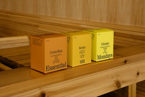 Three colorful coffee packaging boxes labeled Costa Rica Kenya Ethiopia on a wooden shelf showcasing typography design ideal for mockups and branding projects