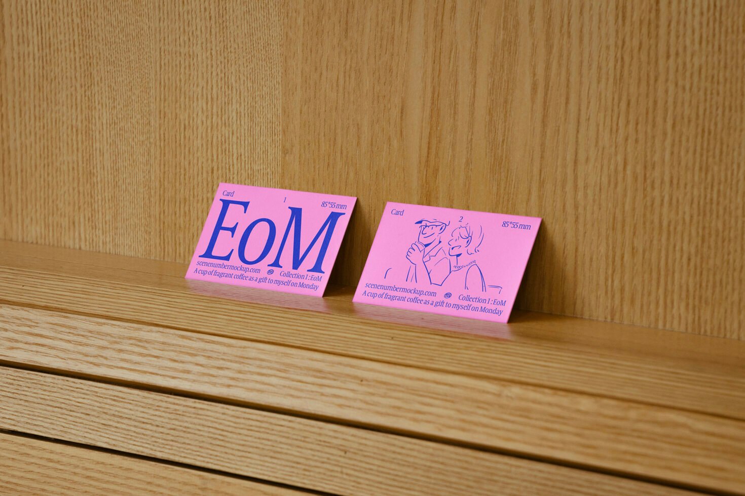 Two pink business cards on wooden surface showcasing bold text and simple illustrations ideal for designers seeking creative mockup templates and graphics.