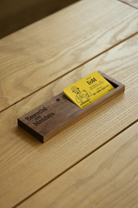 Wooden business card holder with yellow card on light wood surface