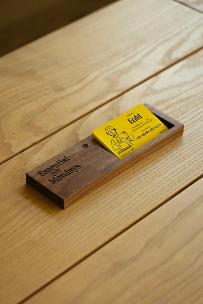 Wooden business card holder with yellow card on light wood surface