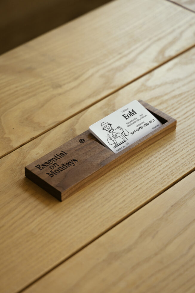 White business card placed on dark wood block on light wood surface