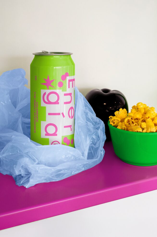 Vibrant mockup with green energy drink can, blue wrap, green bowl of yellow popcorn on a pink surface. Perfect for product design and branding.