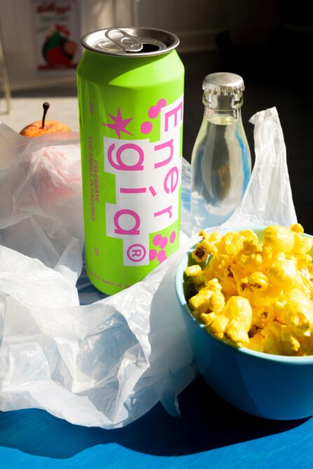 Vibrant energy drink design with green can, popcorn bowl, clear water bottle, and apple. Perfect for mockup projects and designer inspiration. SEO keywords: mockups, design assets.