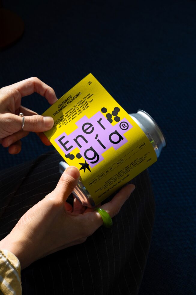 Hand holds a yellow can with creative label design. Energetic branding in focus. Ideal for mockup templates and graphic designers.