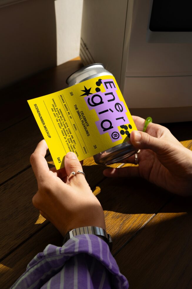 Hands holding a can with a vibrant yellow and purple label design, perfect for mockups. Ideal for graphic designers seeking creative templates and assets.