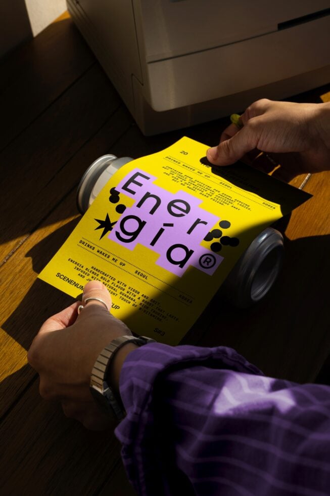 Person holding vibrant yellow printout with bold typography design on wooden table; creative template for modern graphic designers; print mockup.