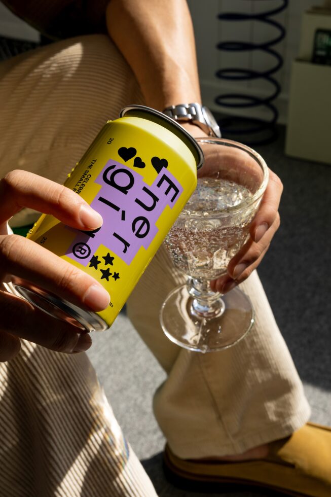Person pouring energy drink from can into glass. Yellow can with modern label. Design mockup concept. Ideal for beverage packaging templates.