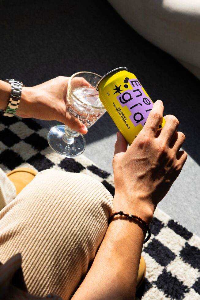 Person pouring a beverage into a clear glass from a colorful can labeled Energia vibrant design showcasing refreshment concept for branding mockups