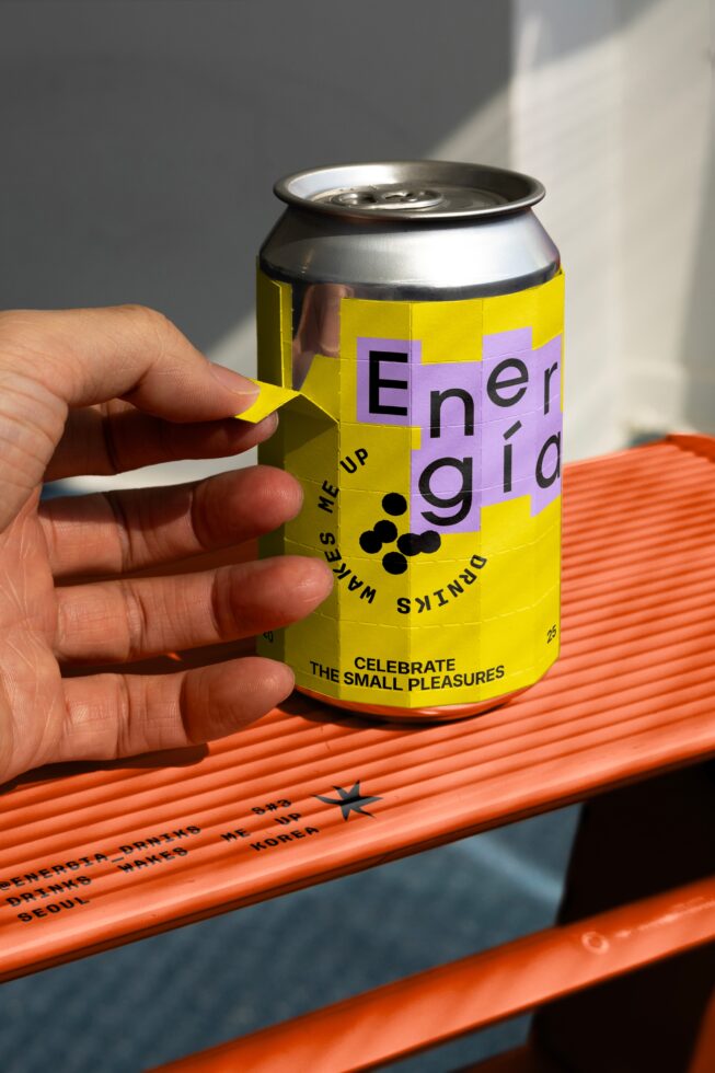 Hand peeling label on energy drink can mockup with vibrant yellow design on orange surface lighting product packaging concept for designers graphics.