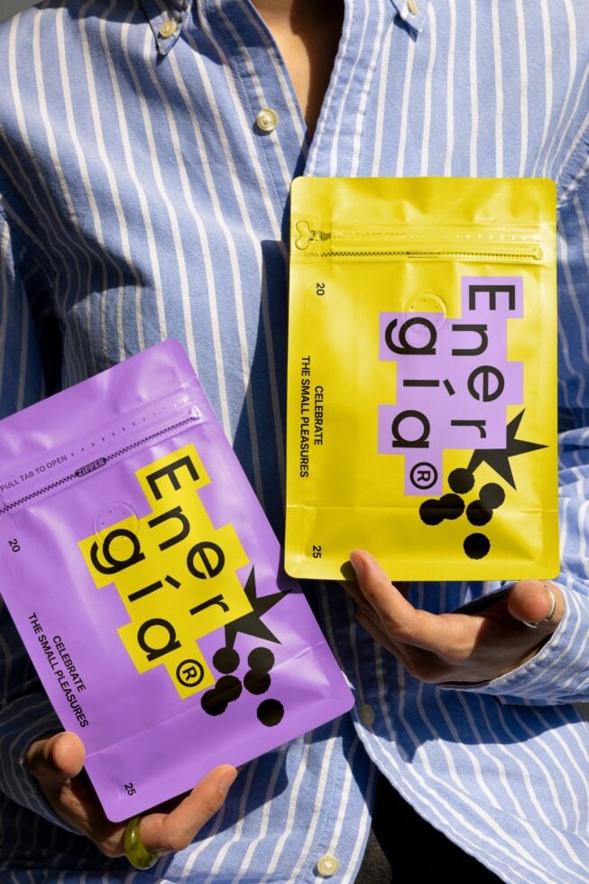 Person holding vibrant packaging in yellow and purple featuring modern typography design ideal for branding mockups and graphic design projects.