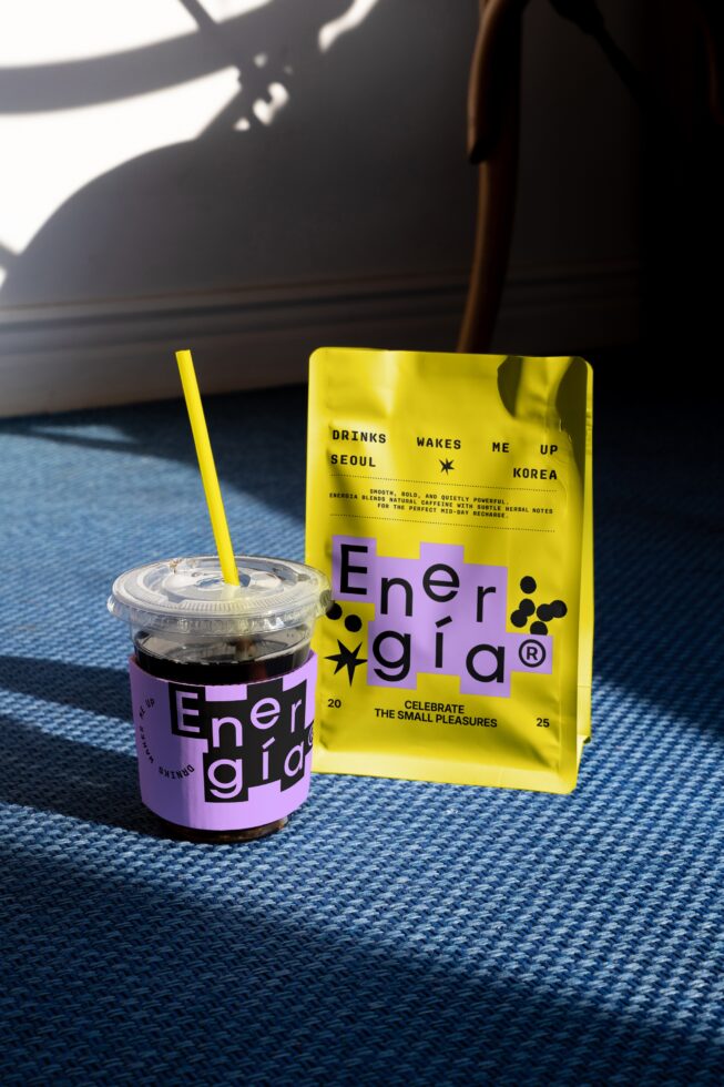 Vibrant coffee packaging mockup featuring a yellow pouch and purple-labeled cup on a blue carpet; perfect for graphic design inspiration.