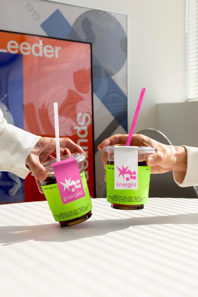 Two hands holding Energia drink cups with colorful branding. Ideal for mockup designs, beverage packaging, graphic design, and marketing concept scenes.