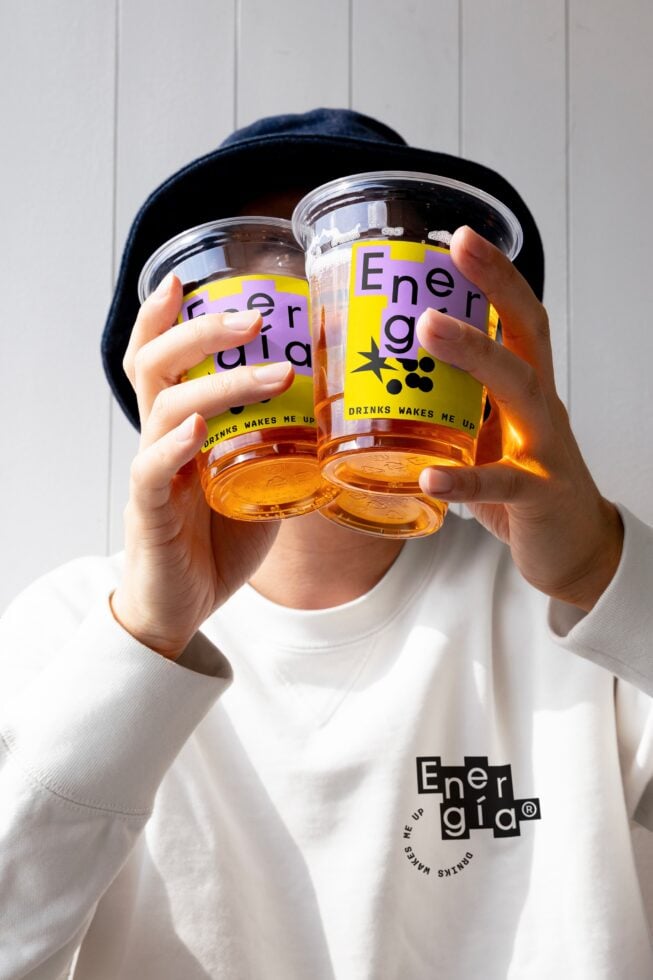 Man holding two drinks with colorful branding. Perfect for mockups packaging designs. Keywords: design mockup packaging cups branding graphics.