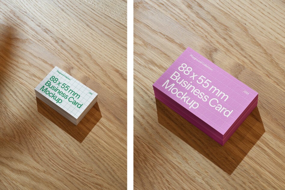 Two business card stacks in pink plus white versions on wooden surface