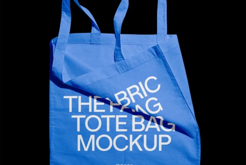 Blue fabric tote bag mockup with white text isolated on black background for designers. Perfect for showcasing custom designs and branding.