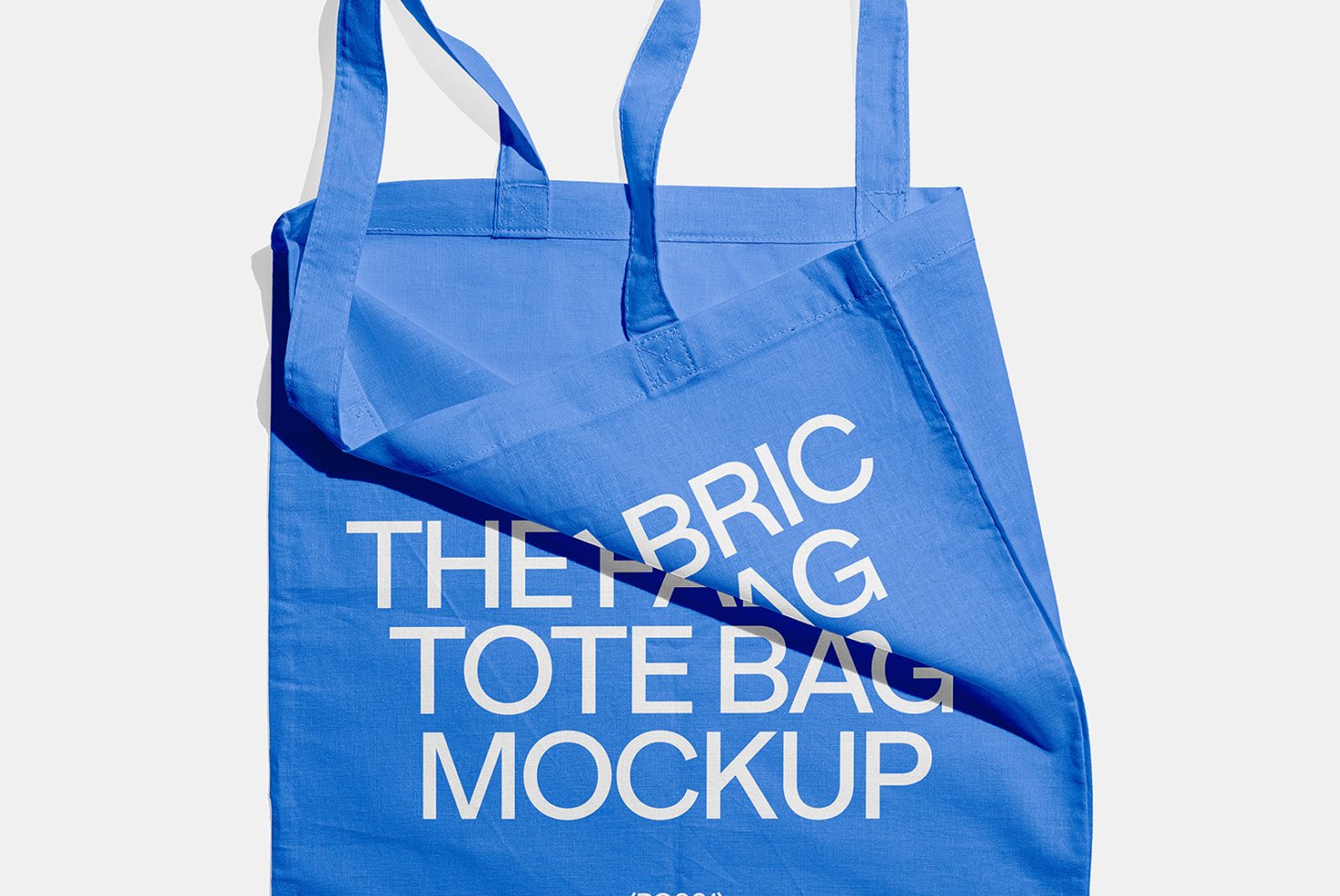 Blue fabric tote bag mockup with bold white text overlay. Ideal for showcasing branding designs, personalized logos, and eco-friendly product templates.