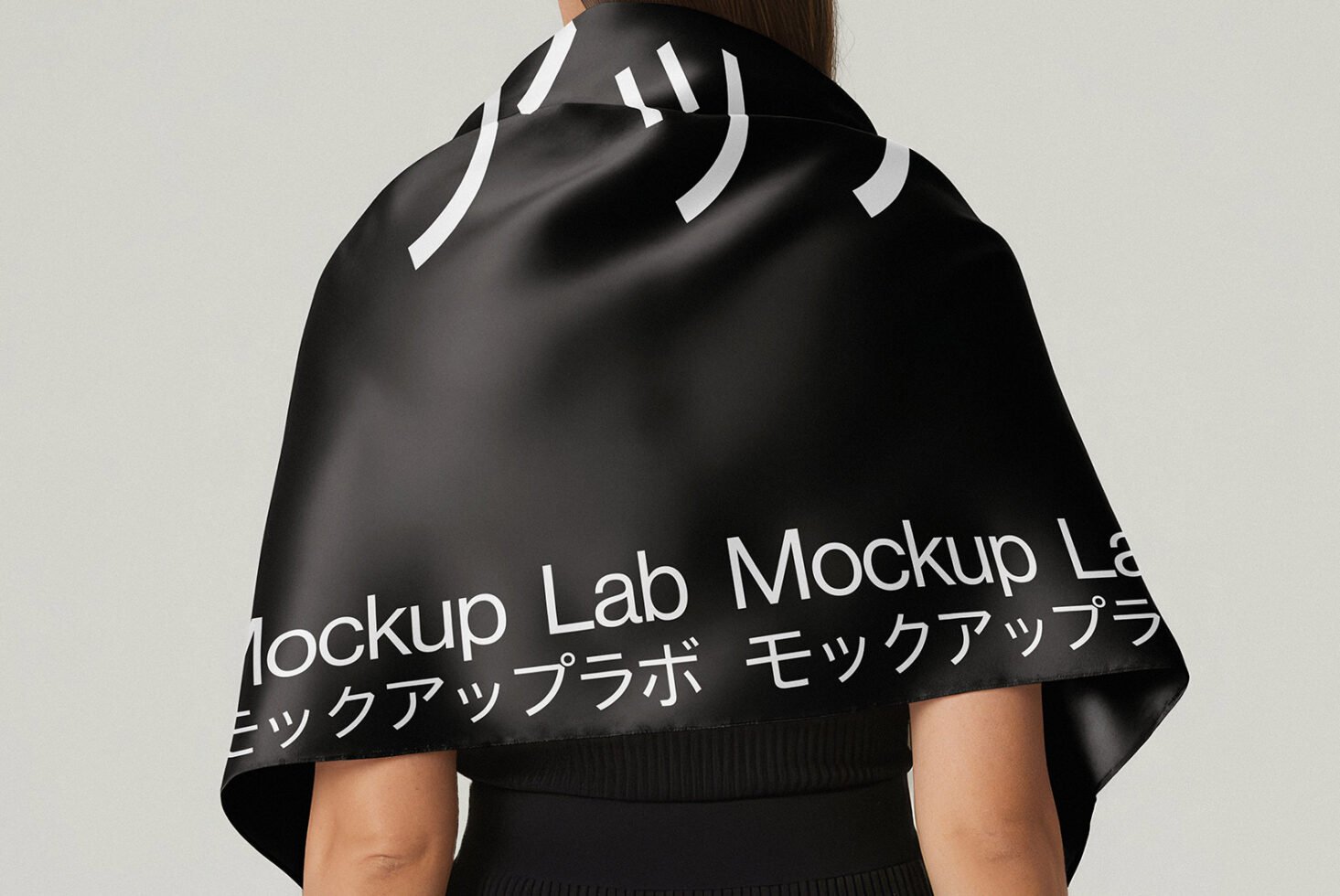 Mockup of a person wearing a black scarf with white text in English and Japanese. Ideal for fashion designers and graphic designers seeking stylish templates.