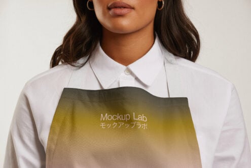 Close-up of a female model wearing a white shirt and an apron with a gradient design and text Mockup Lab; perfect for apparel mockup templates.