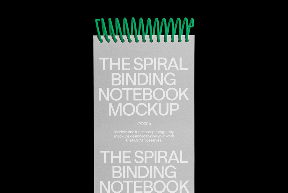 Light gray spiral notebook with green metal binding on black background