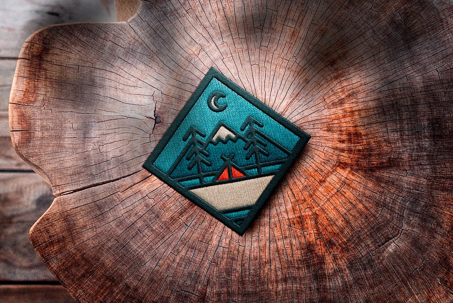 Camping patch design featuring mountains and trees on wood background. Ideal for mockups, graphics, templates. Outdoors, nature, embroidery, texture.
