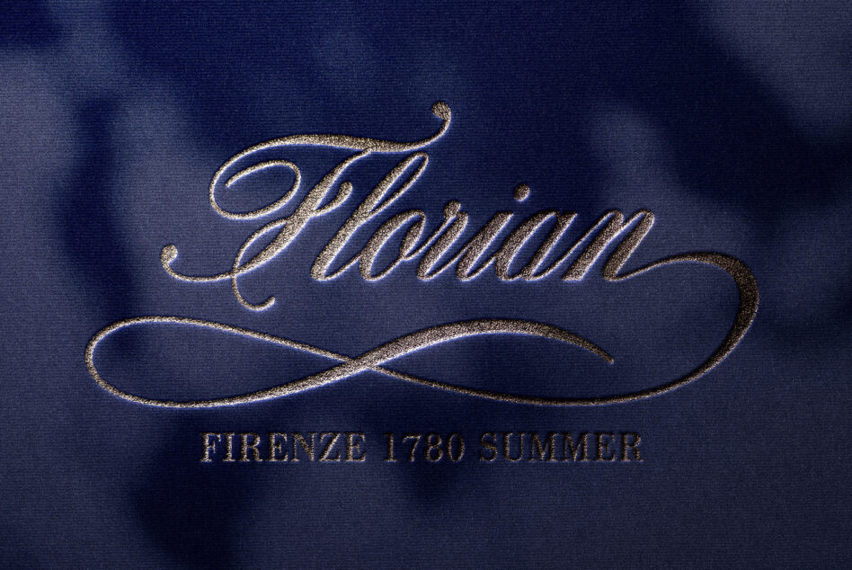 Ornate italic text with decorative underline in gold foil on blue fabric