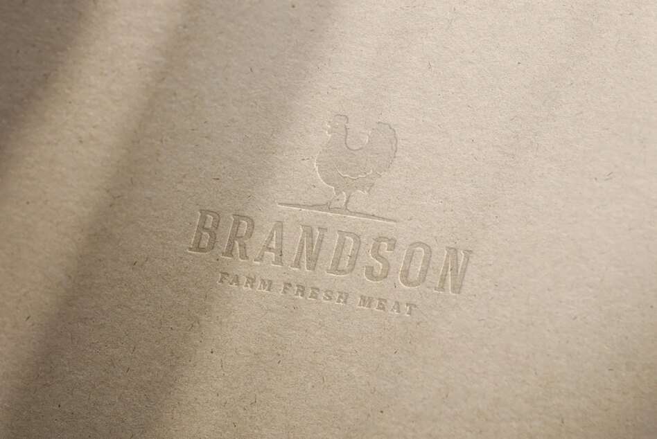 Mockup of embossed logo on textured paper featuring a chicken silhouette above the text Brandson Farm Fresh Meat. Ideal for branding design projects.