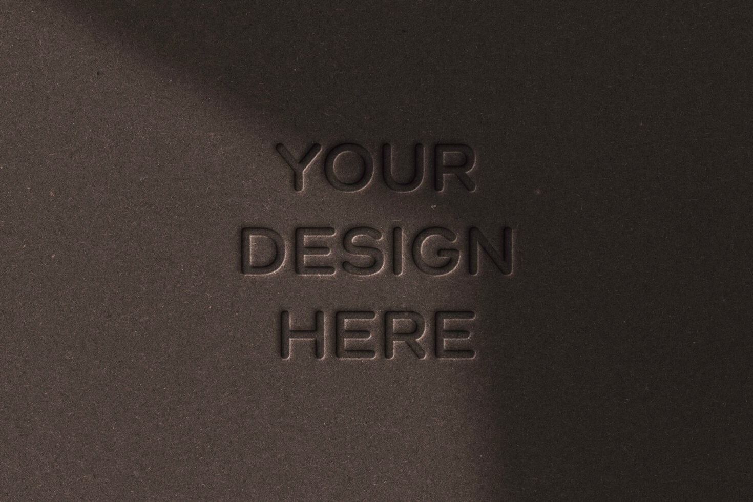 Your Design Here text embossed deeply into dark brown grainy surface mockup