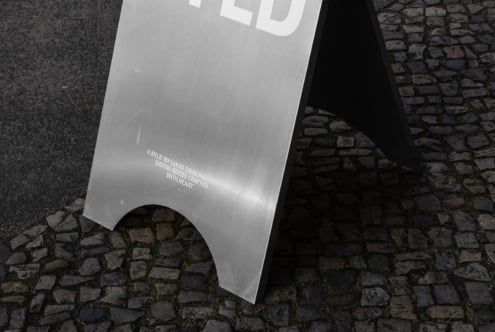 Aluminum sign mockup on cobblestone street ideal for realistic street scene presentations fonts branding and graphic design showcasing urban aesthetics.
