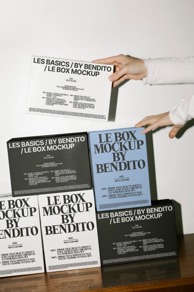 Box mockup designs by Bendito in white and black packaging arranged on a wooden surface. Perfect for designers seeking customizable templates.
