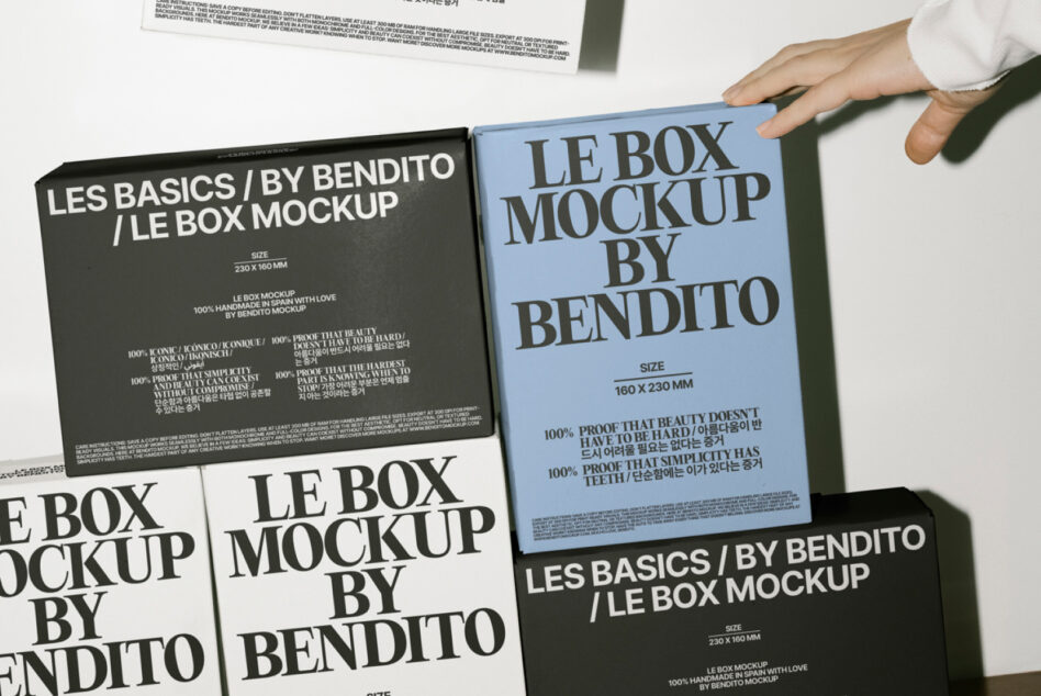 Hands presenting black box mockup next to light blue version on table