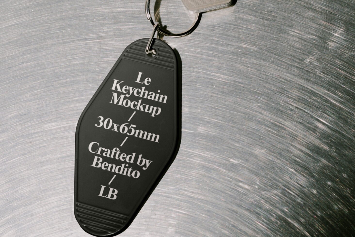 Black keychain mockup on metal surface for designers crafted by Bendito in 30x65mm size ideal for graphic and template projects featuring LB branding.